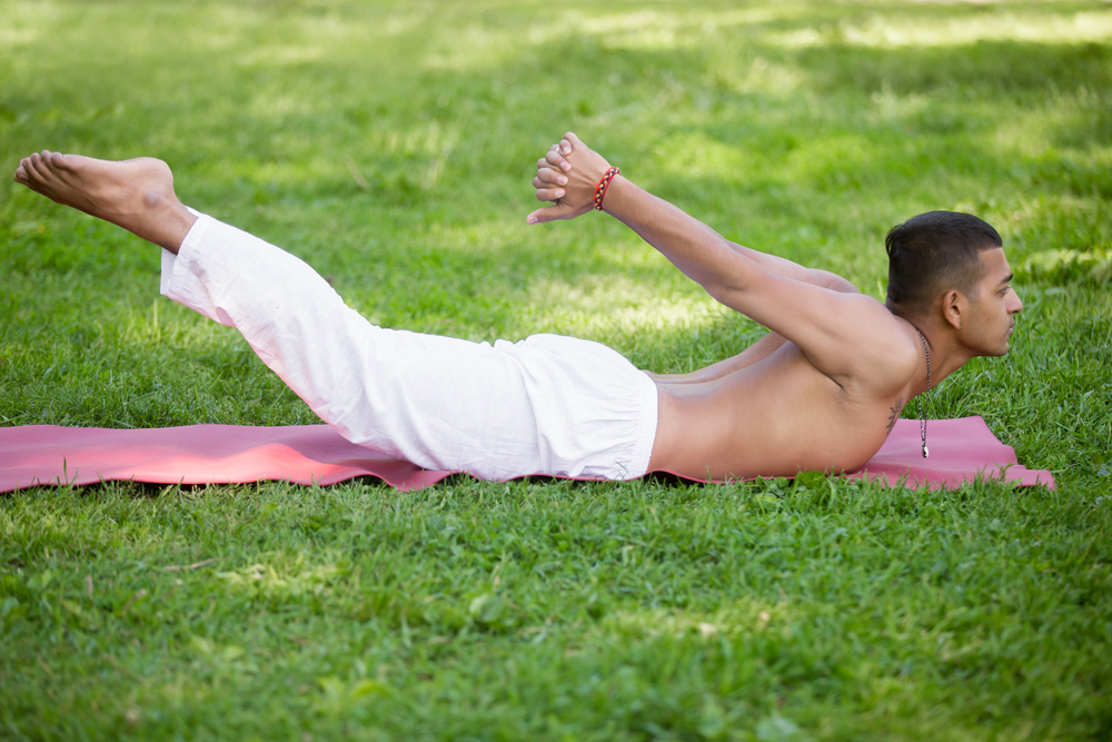 a man does a back extension on a mat in the grass