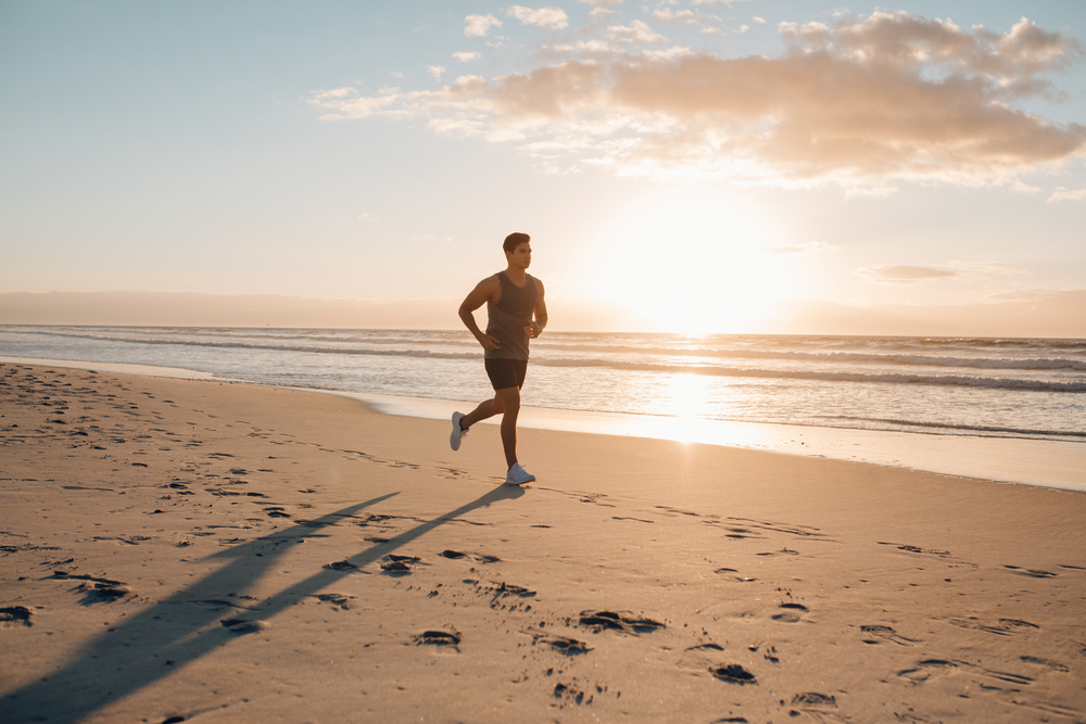 person running on the beach at sunset