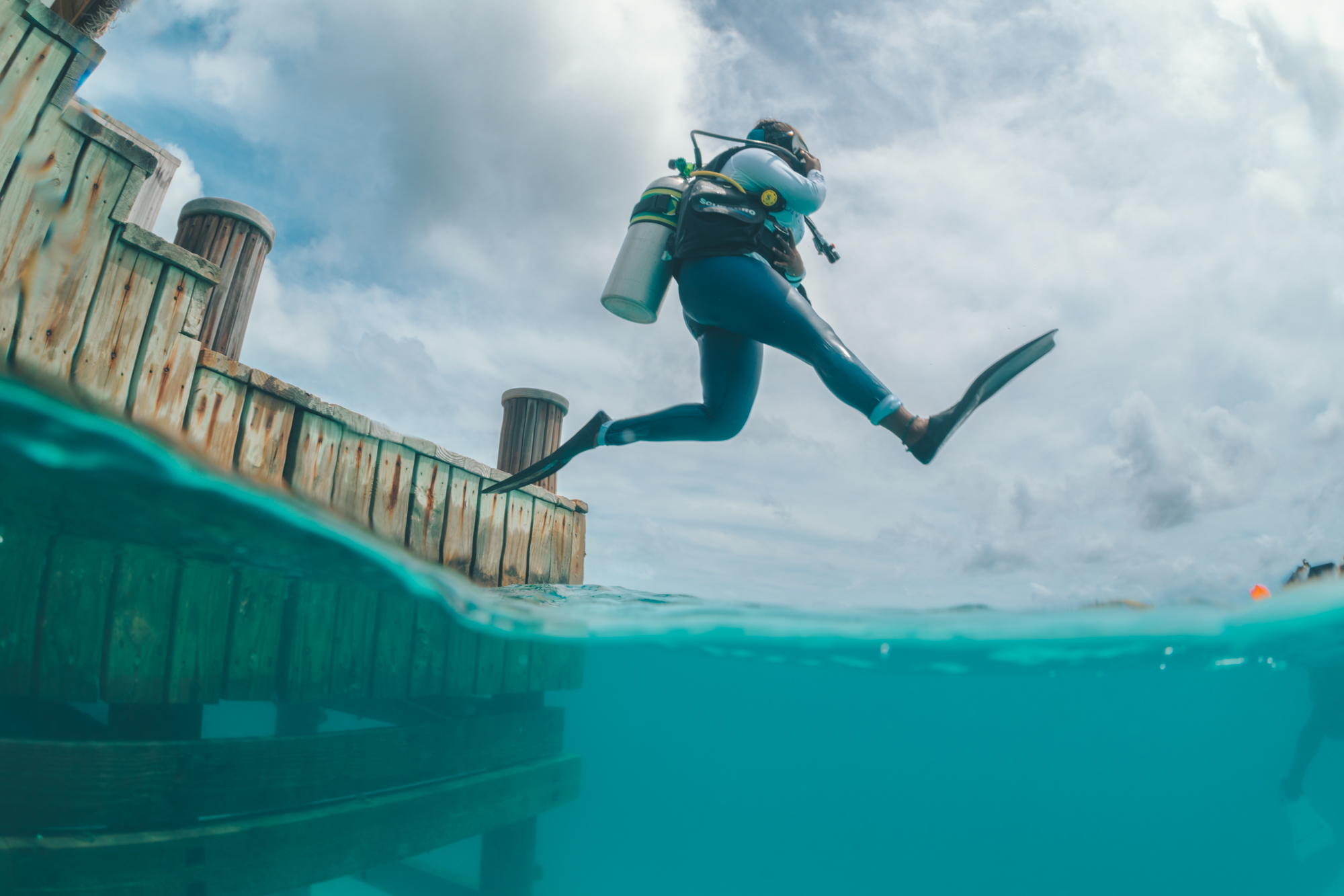 A woman takes a giant stride off a dock in the Maldives