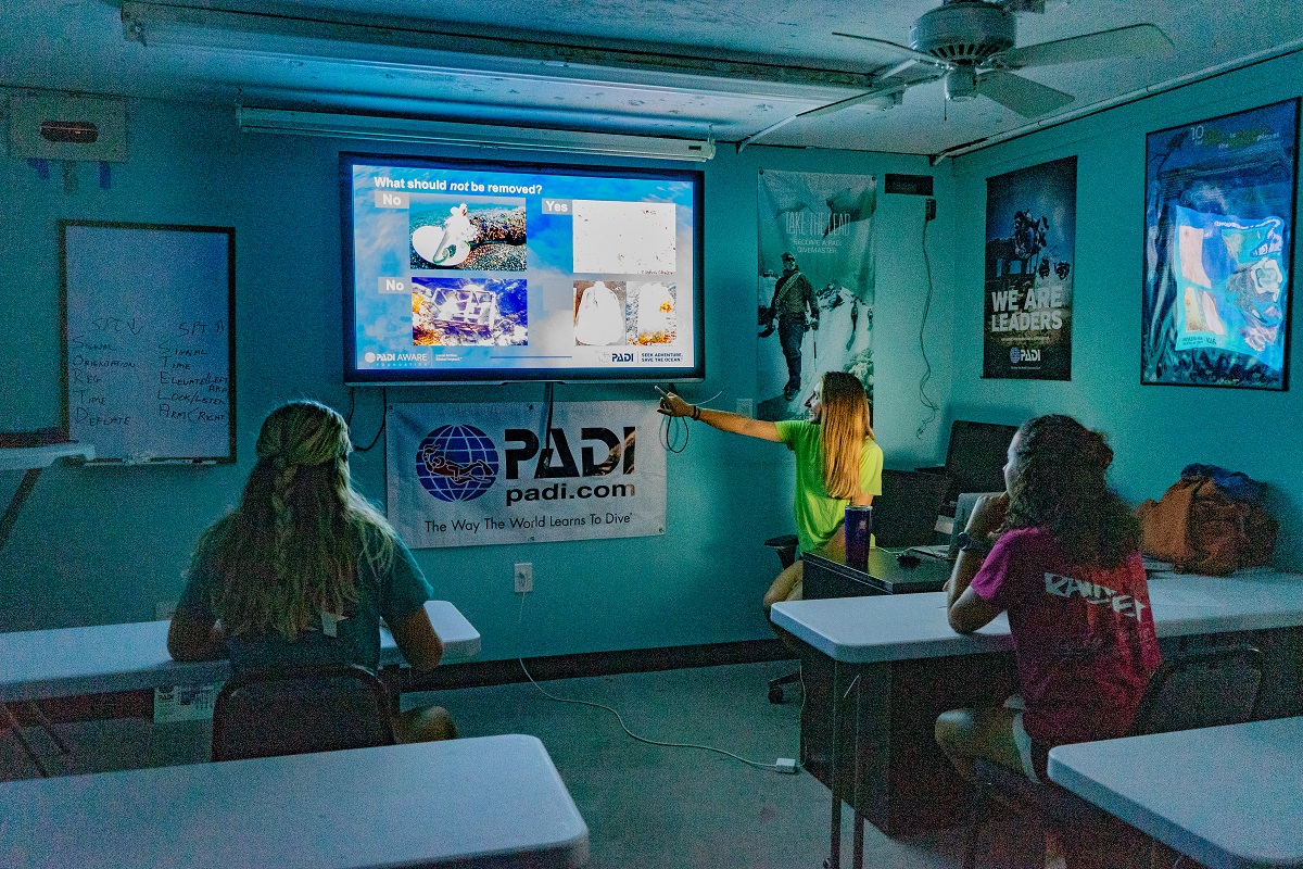 Students look on as a dive professional goes through the Dive Against Debris course on a screen.