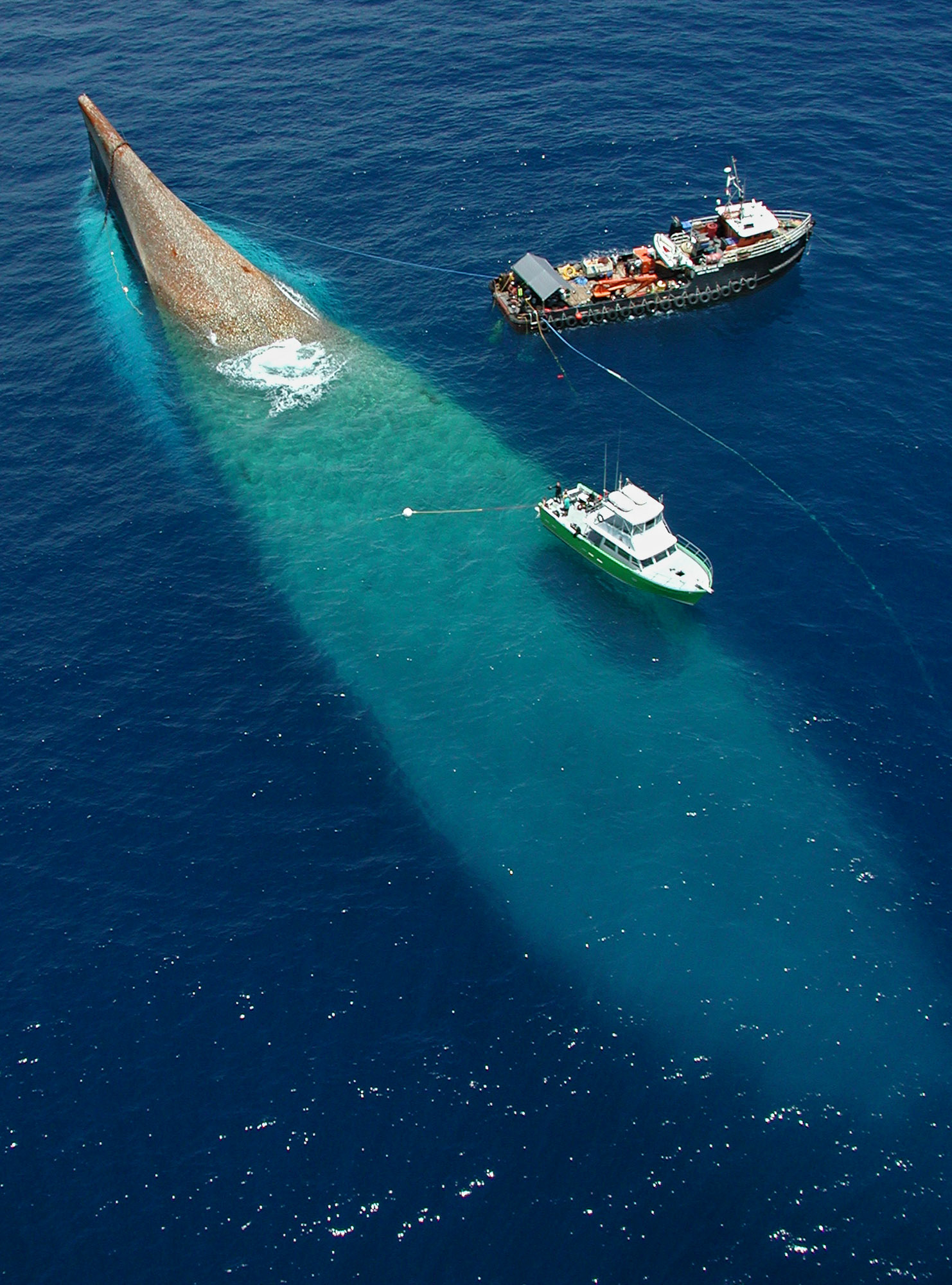 A ship sits upside-down at the surface after it sank prematurely.
