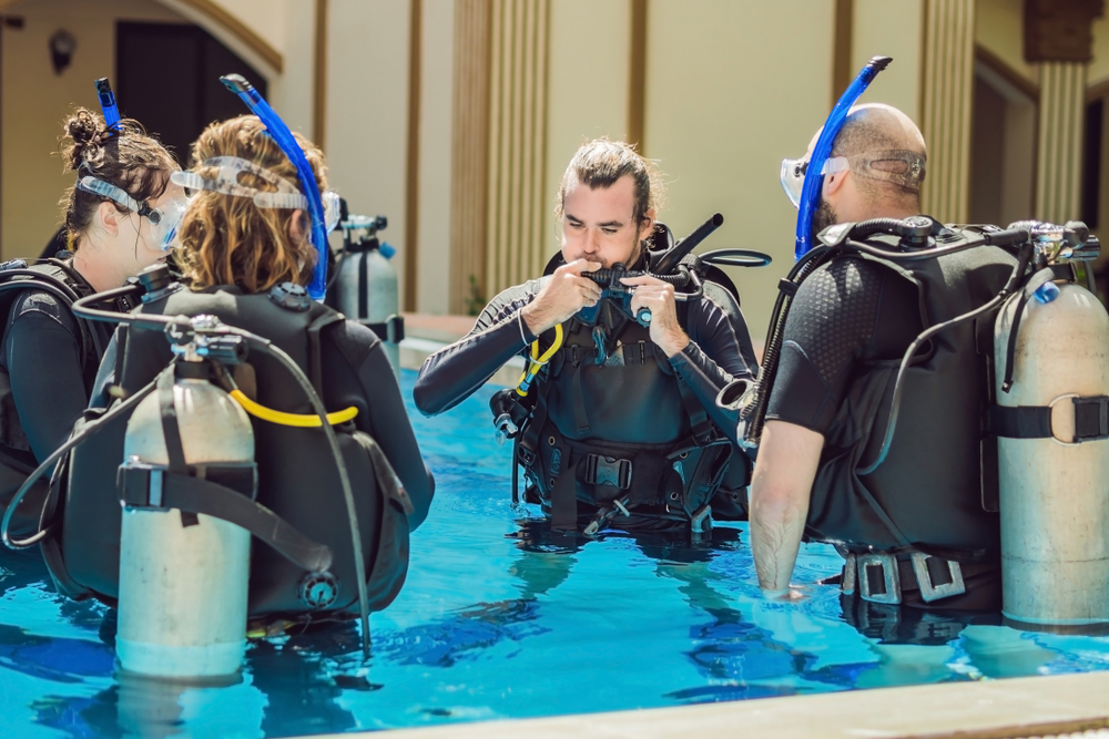 a diver manually inflates their BC while standing in a pool