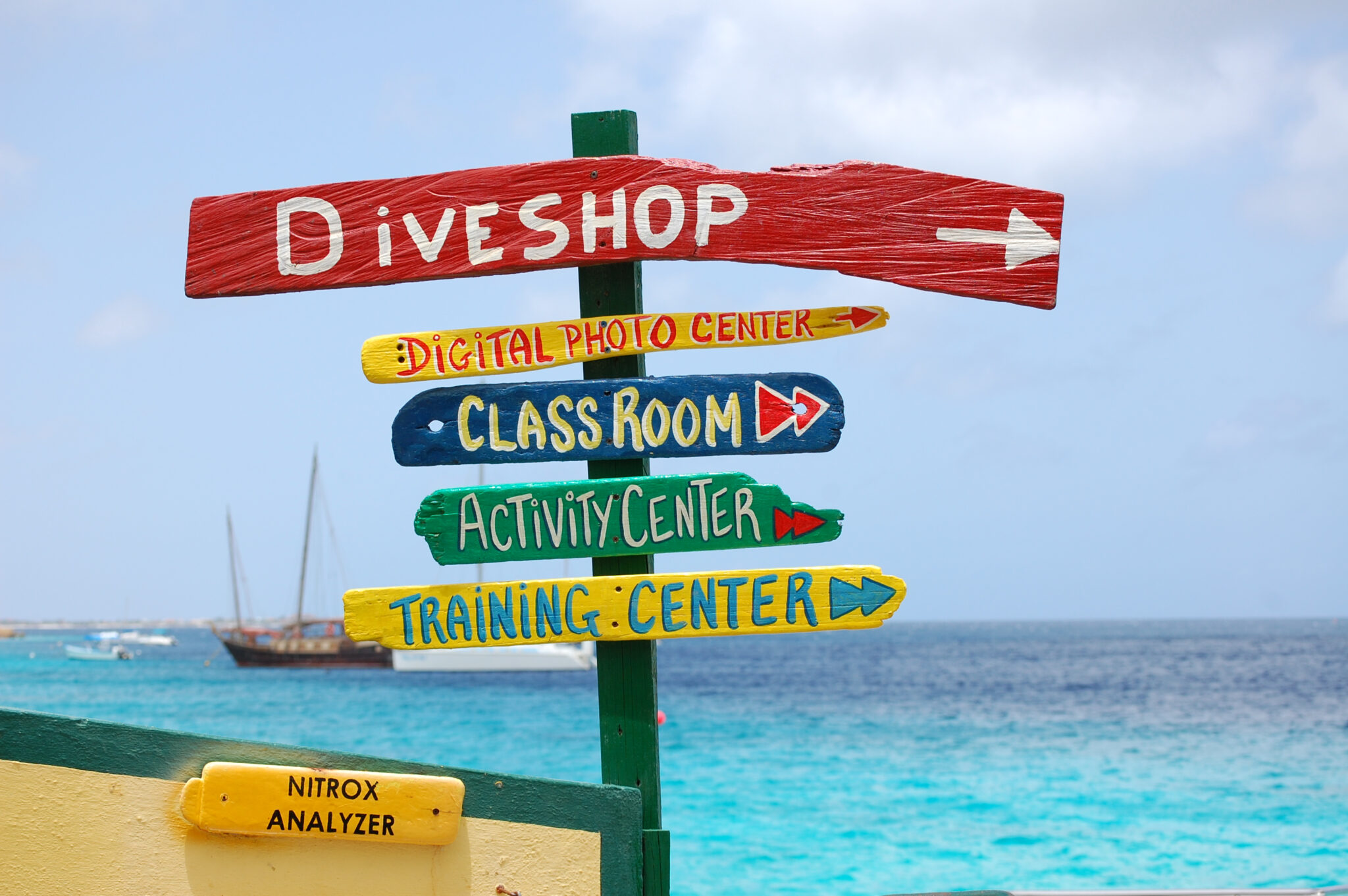 a post with colorful wooden signs pointing to the dive shop