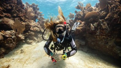 a female diver floats in a shallow underwater canyon