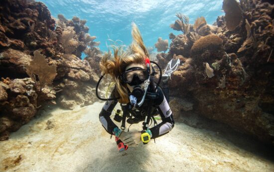 a female diver floats in a shallow underwater canyon