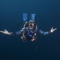 A woman diver floats effortlessly with her hands outstretched.