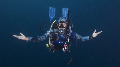 A woman diver floats effortlessly with her hands outstretched.