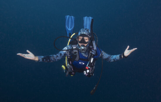 A woman diver floats effortlessly with her hands outstretched.
