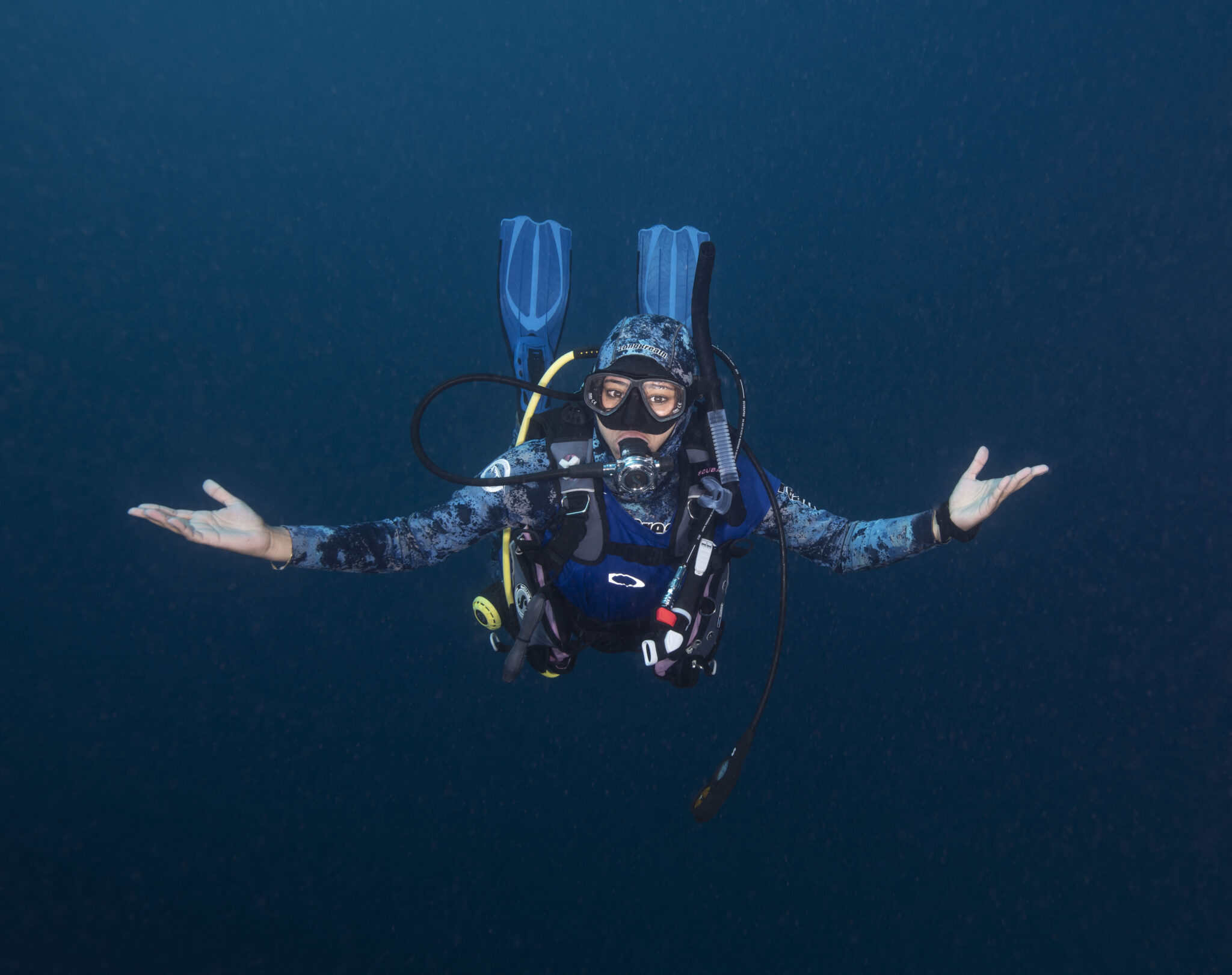 A woman diver floats effortlessly with her hands outstretched.