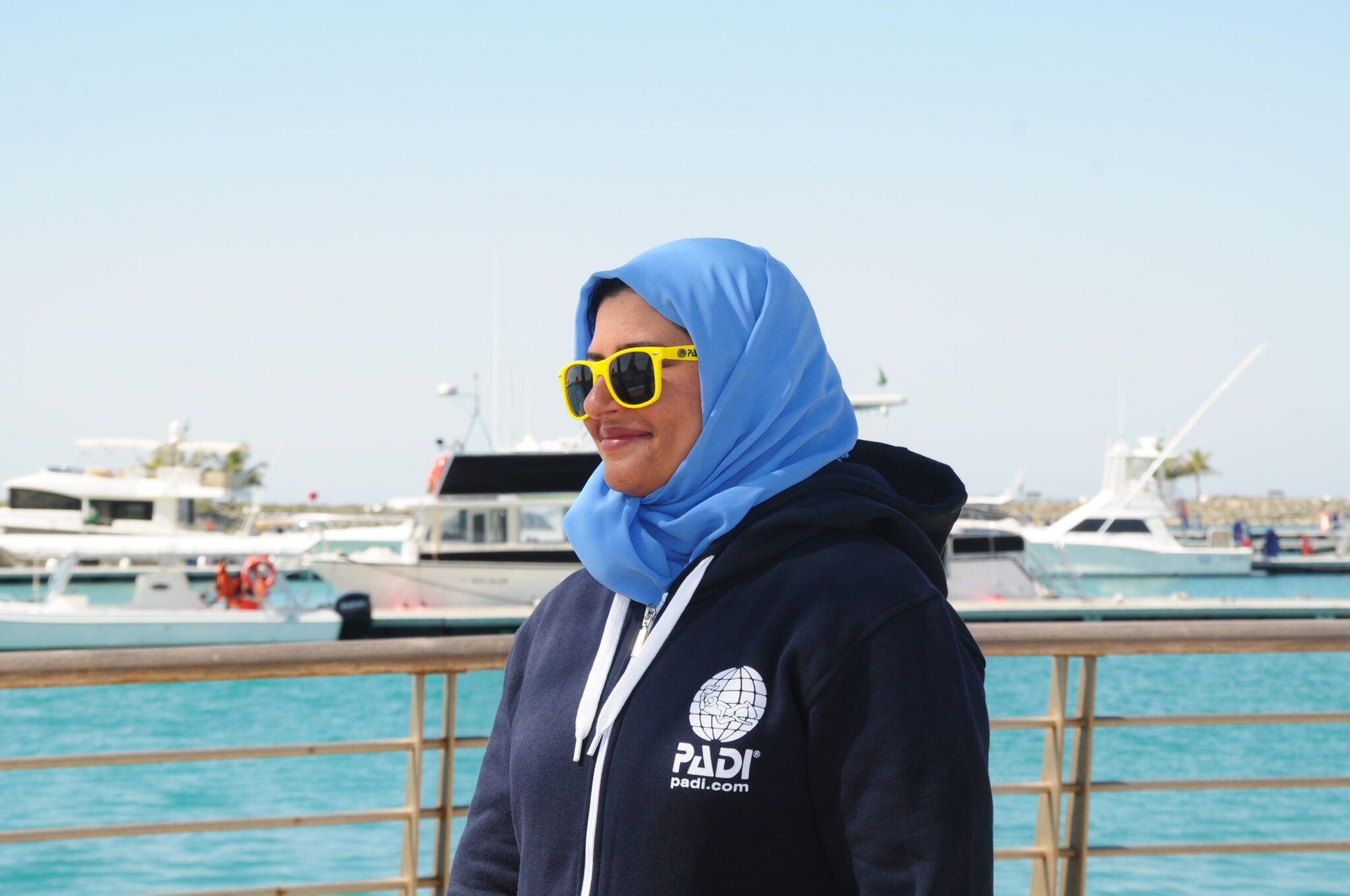 A female diver wears a PADI jacket and a headscarf.