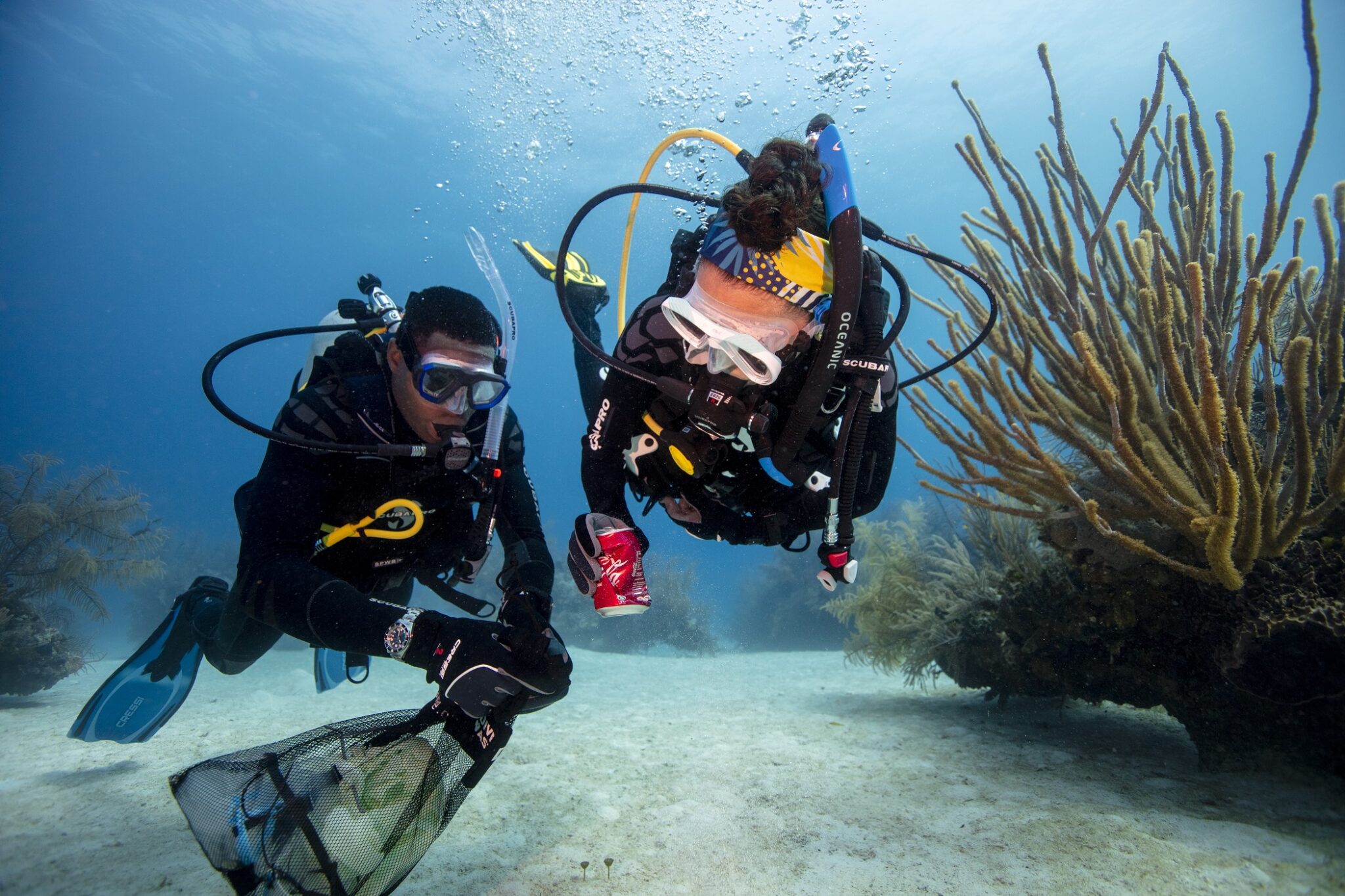 two divers collect debris trash underwater