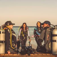 Divers ready to take ocean conservation action this AWARE Week. Divers are gearing up with a beautiful ocean background.