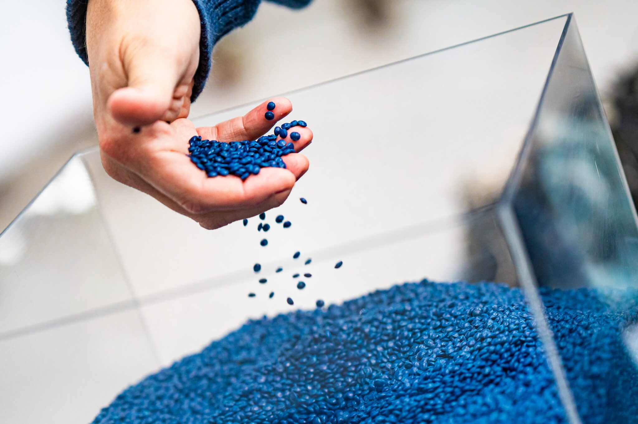 A hand strains blue plastic nurdles made from recycled marine debris from the Great Pacific Garbage Patch