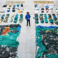 A man stands between two rows of organized marine plastics