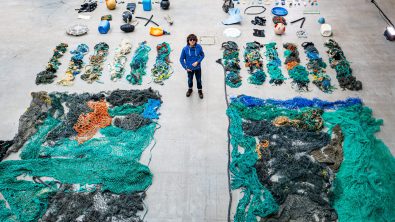 A man stands between two rows of organized marine plastics