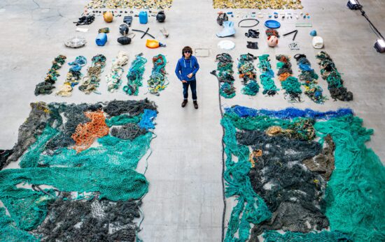 A man stands between two rows of organized marine plastics