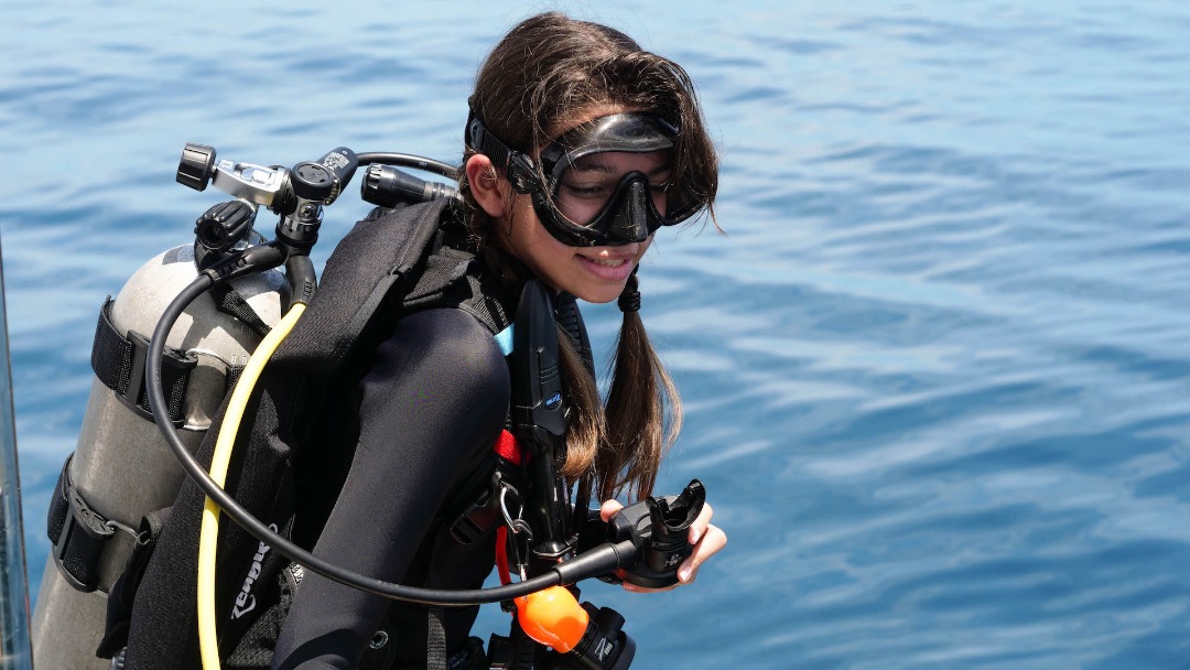 PADI AmbassaDiver and Junior Divemaster Julia prepares to go scuba diving from a boat.
