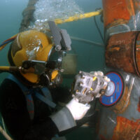 A commercial diver doing underwater grinding to repair the OSS Ogden