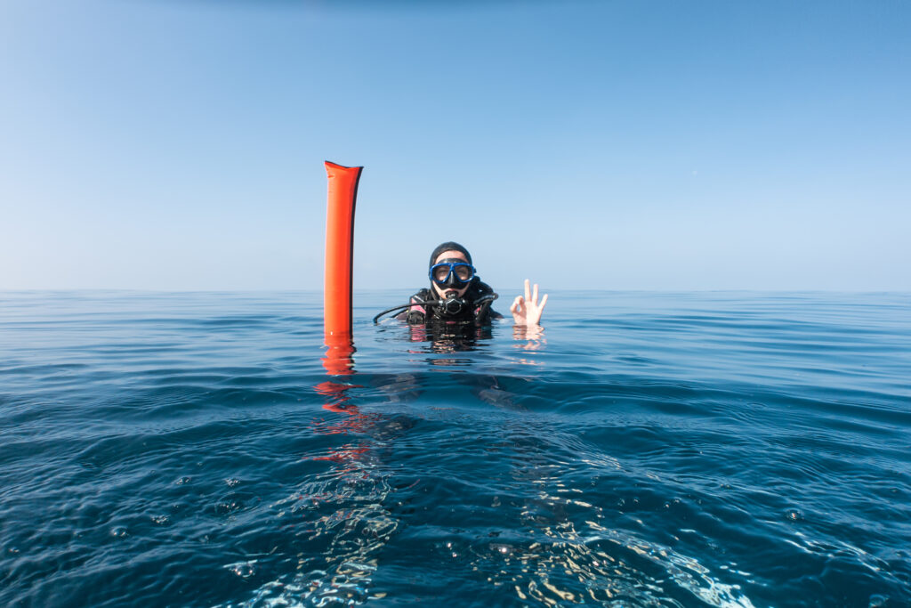 diver alone at the surface with DSMB orange safety sausage