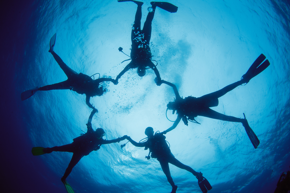 divers hold hands in a circle underwater