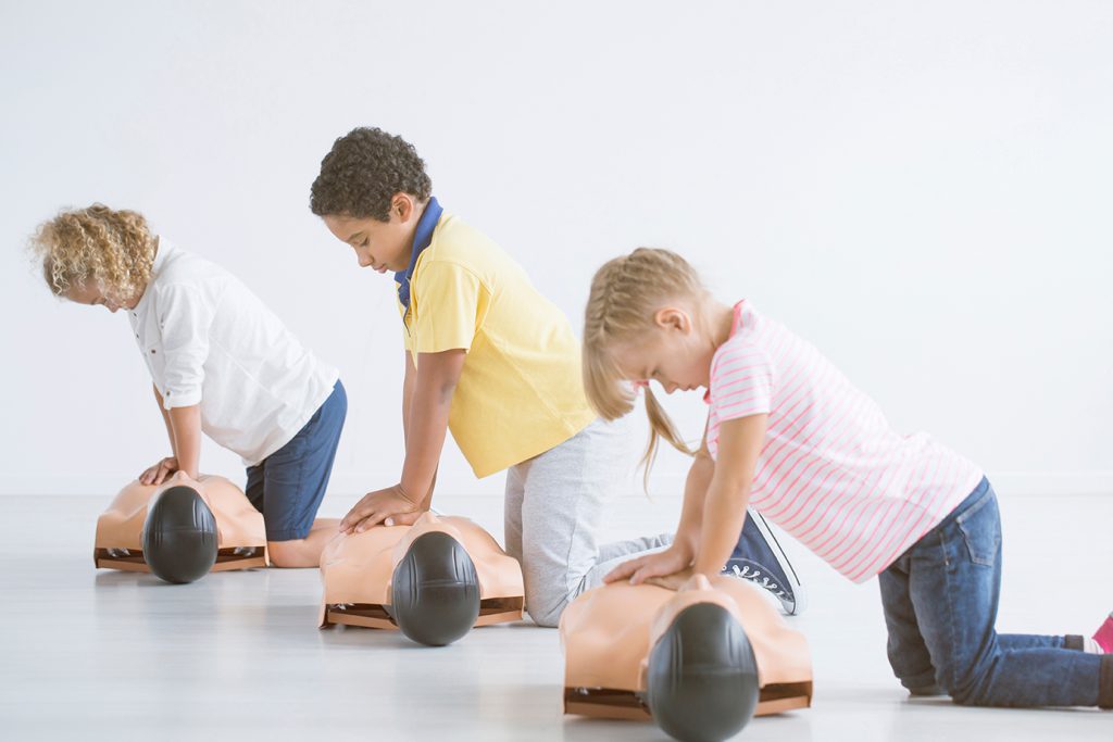 three children performing CPR on dummies