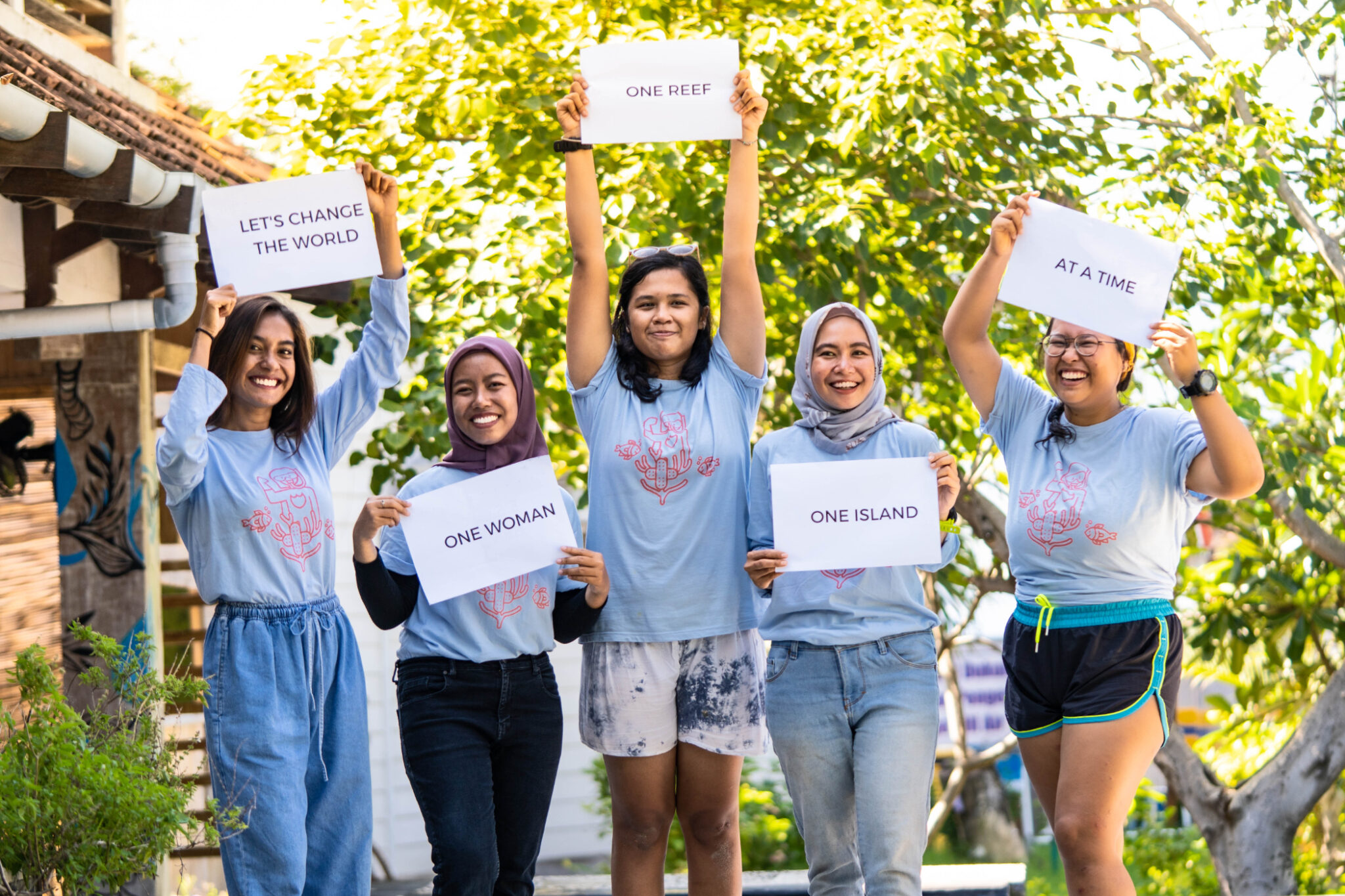 The coral catch women of Gili Shark hold up signs