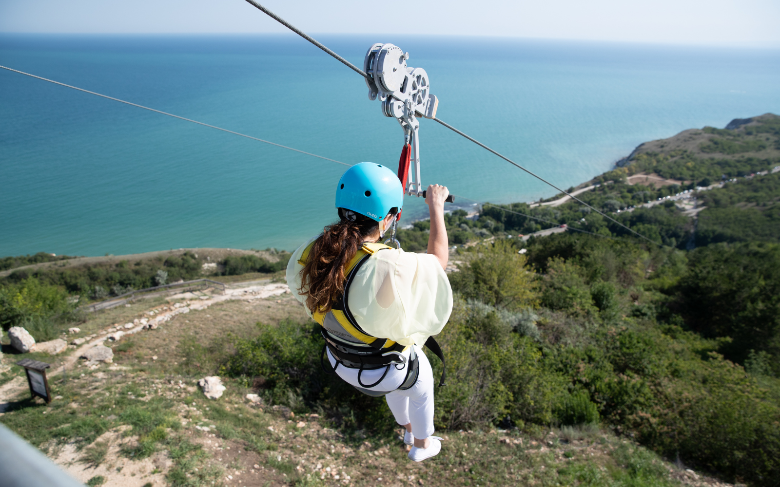 A girl ziplines from the top of a mountain to the sea, a high-altitude activity that should be avoided following a scuba dive
