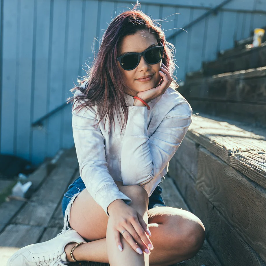 woman wearing padi sunglasses while sitting on steps outside