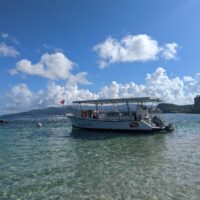 A dive boat is tied to a buoy in front of a beautiful shoreline in Grenada