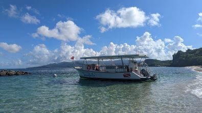 A dive boat is tied to a buoy in front of a beautiful shoreline in Grenada