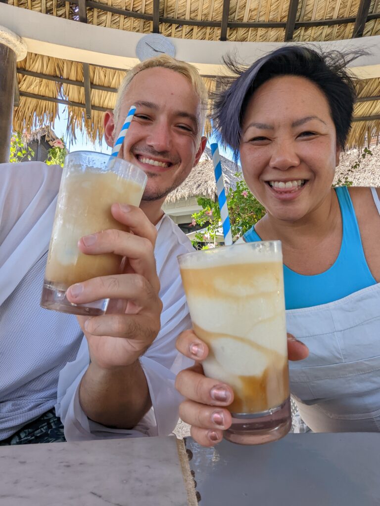 Two friends hold up frozen drinks at Sandals Resorts.