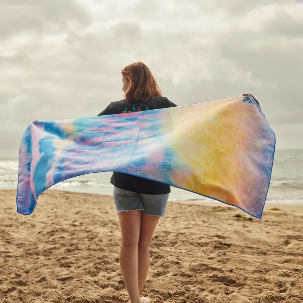 A woman holding up a PADI Gear parrotfish recycled plastic beach towel, one of the best scuba diving gifts for any age