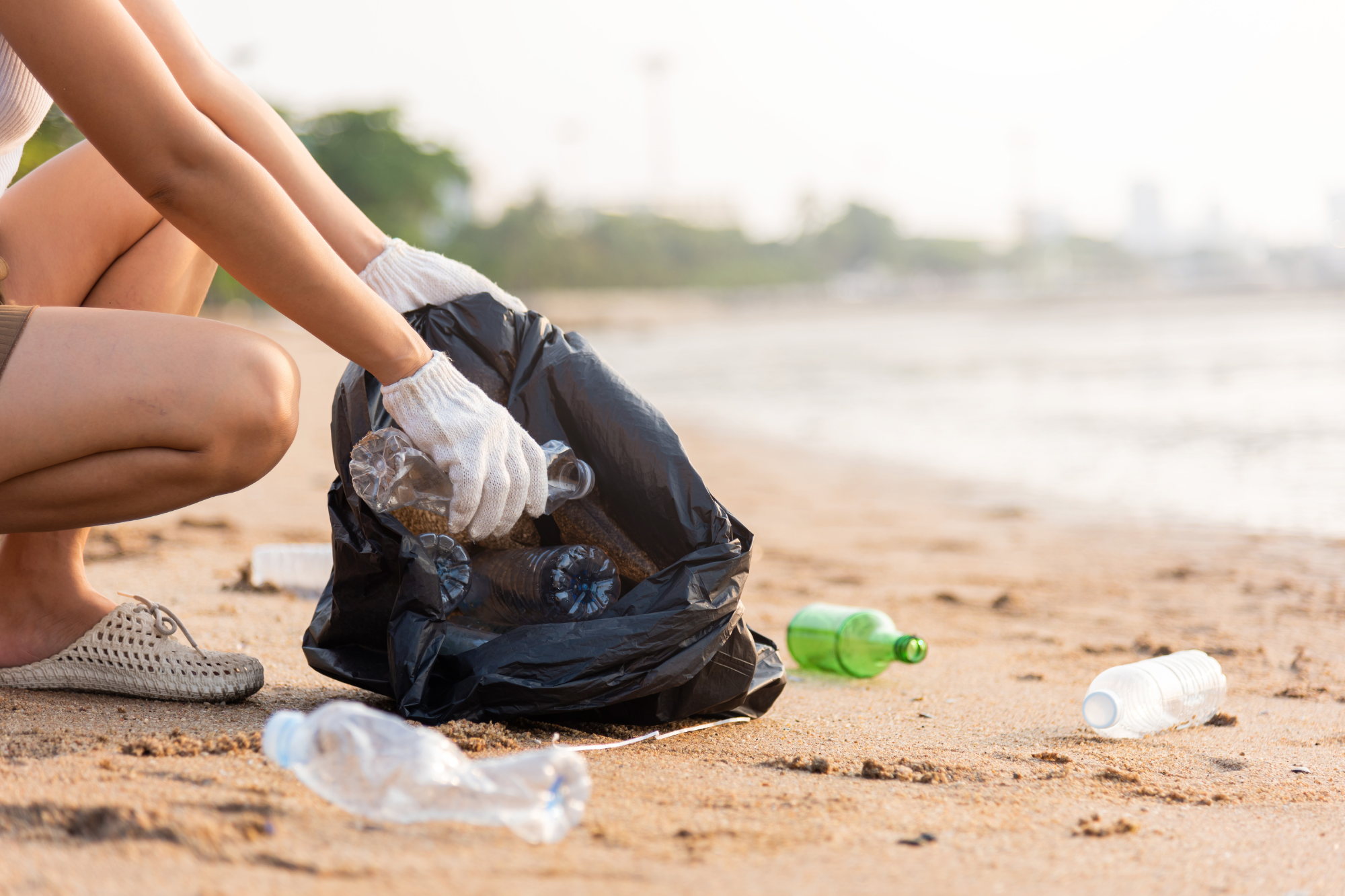 Person picking up debris on the beach