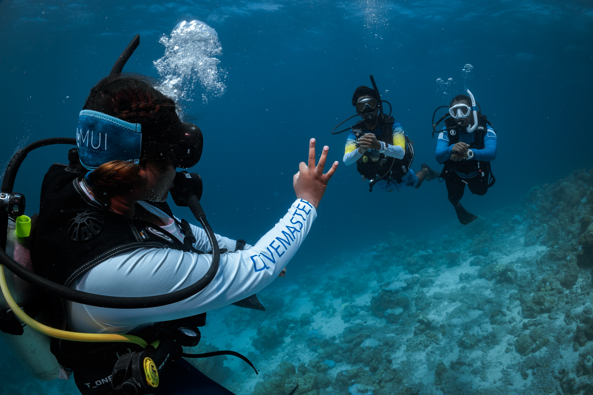 PADI Pro leading students during a dive, checking on them and giving the okay hand signal