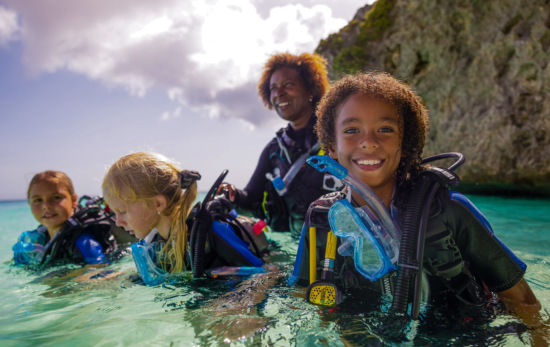 a group of kids goes diving in the ocean and smiles topside