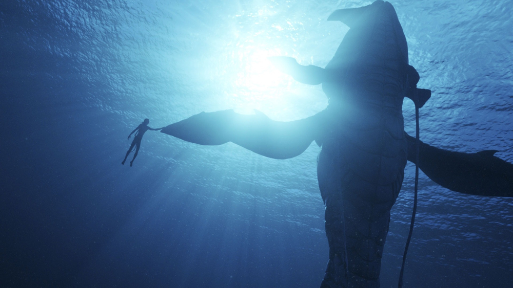 A freediver floats next to a whale-like creature on the set of Avatar: The Way of Water