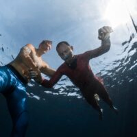 a diver practices static apnea breath hold freediving in shallow water with a trained buddy