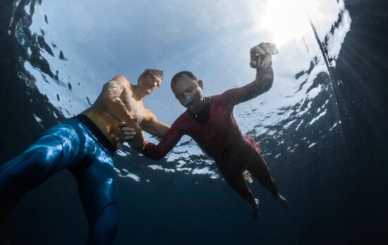 a diver practices static apnea breath hold freediving in shallow water with a trained buddy