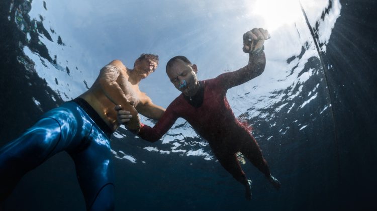 a diver practices static apnea breath hold freediving in shallow water with a trained buddy