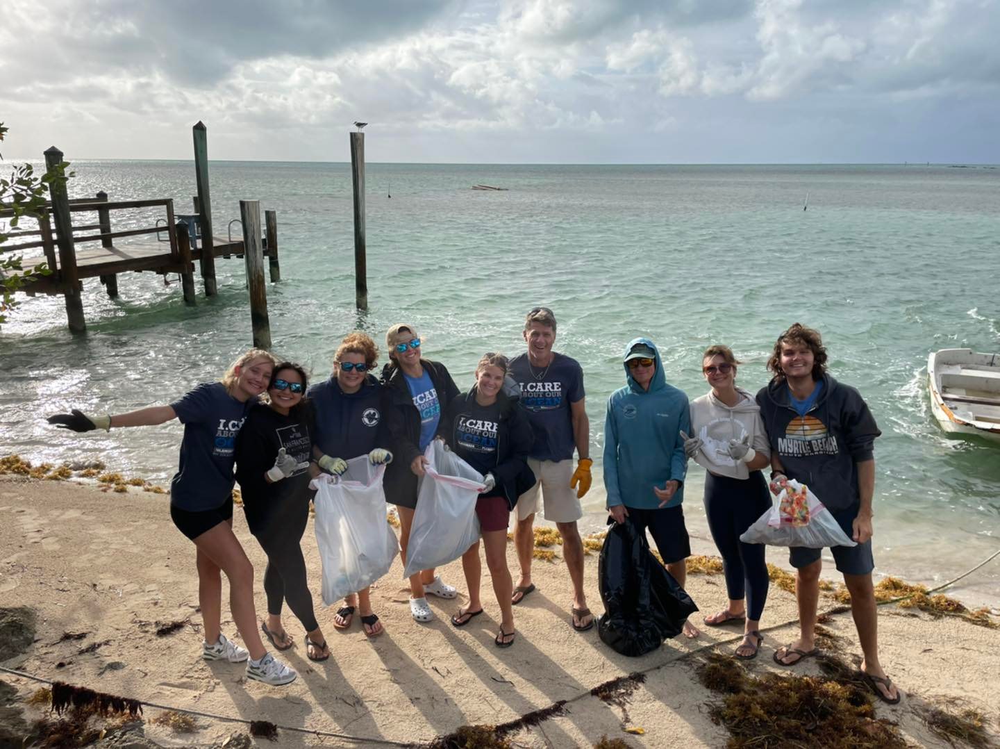 A group of divers and ocean adovcates clean up a shoreline in the Florida Keys. They're holding bags of trash.