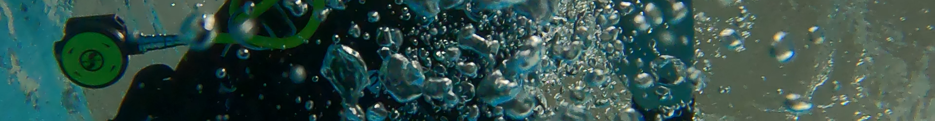a woman looks at an underwater camera and blows bubbles