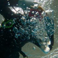 a woman looks at an underwater camera and blows bubbles