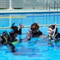 Students learning scuba diving skills in confined water during a PADI Open Water Diver course