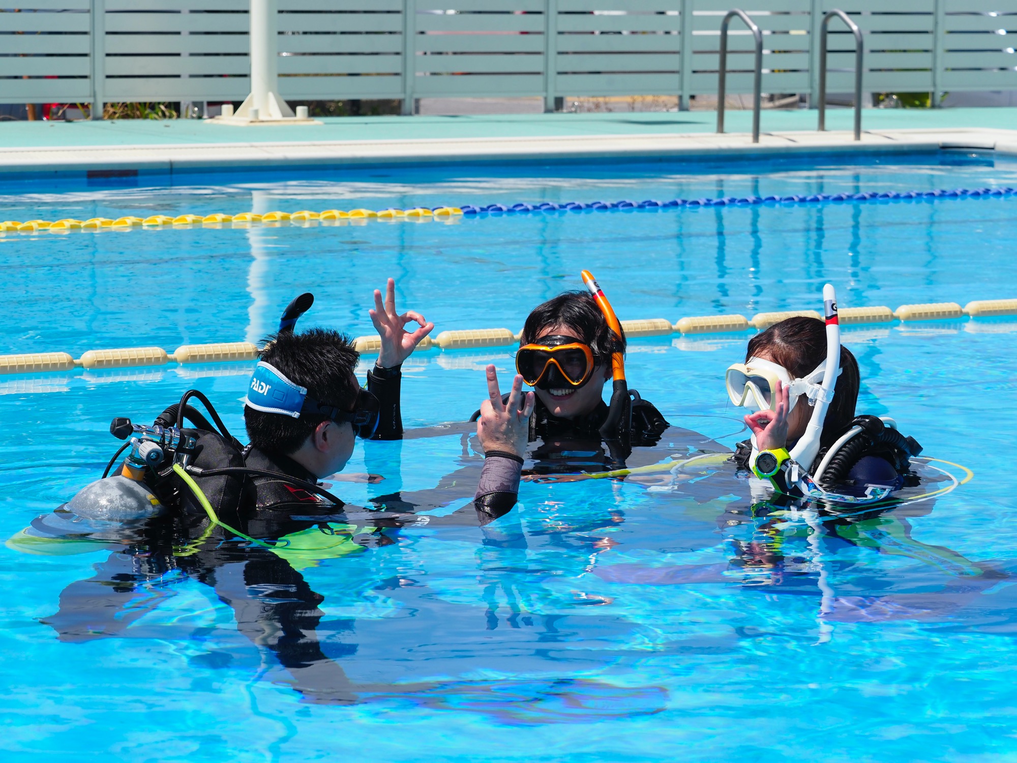 A group of PADI Open Water Diver students learning scuba skills in confined water along with the support of a PADI Divemaster