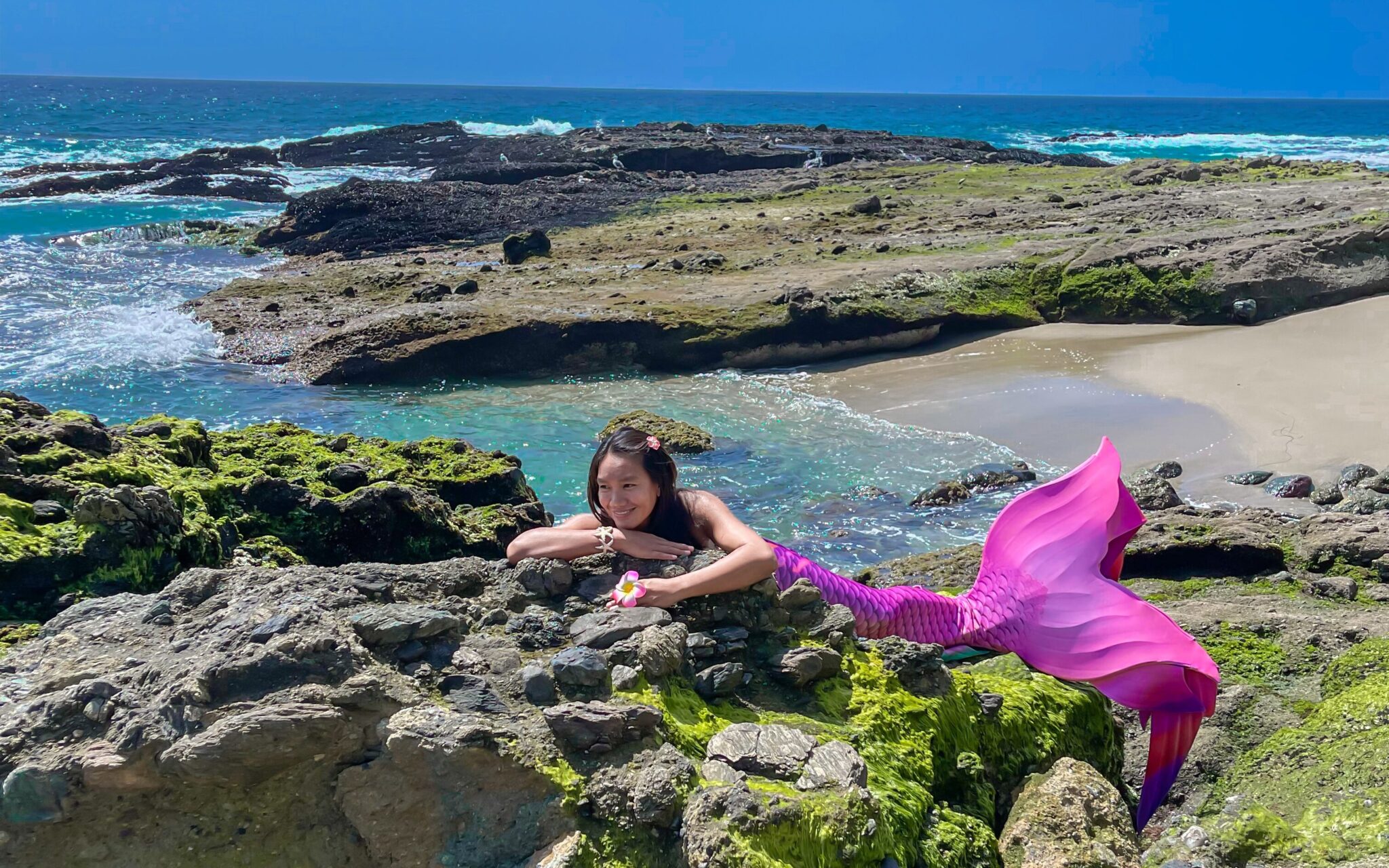 Pro Mermaid Great Chin Burger @guam_babe_freediver on a rocky beach with a pink tail