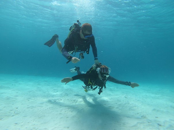 A buddy diver assists another on an adpative dive.
