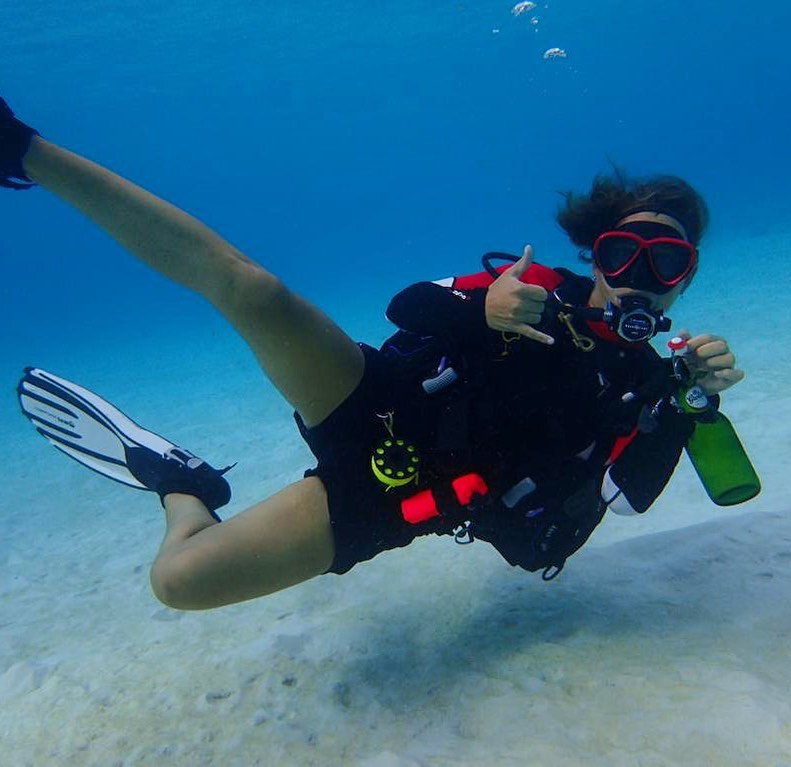 Lyanca Hoiting holds up a hang-ten sign while diving