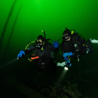 two padi underwater navigators explore the underwater world in Germany with flashlights