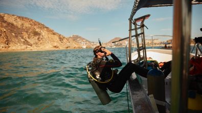 a diver safely rolls backwards off a boat in cabo san lucas, mexico