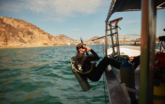 a diver safely rolls backwards off a boat in cabo san lucas, mexico